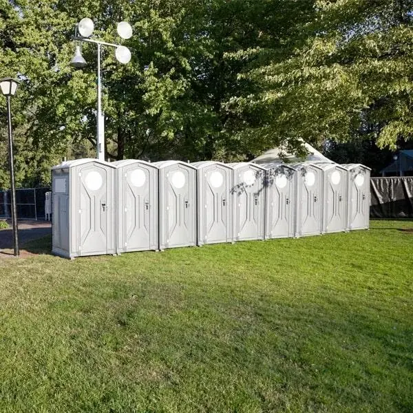 A line of portable restrooms set along a grassy outdoor venue