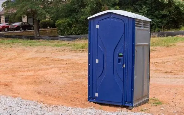 Blue portable toilet positioned beside an outdoor event area